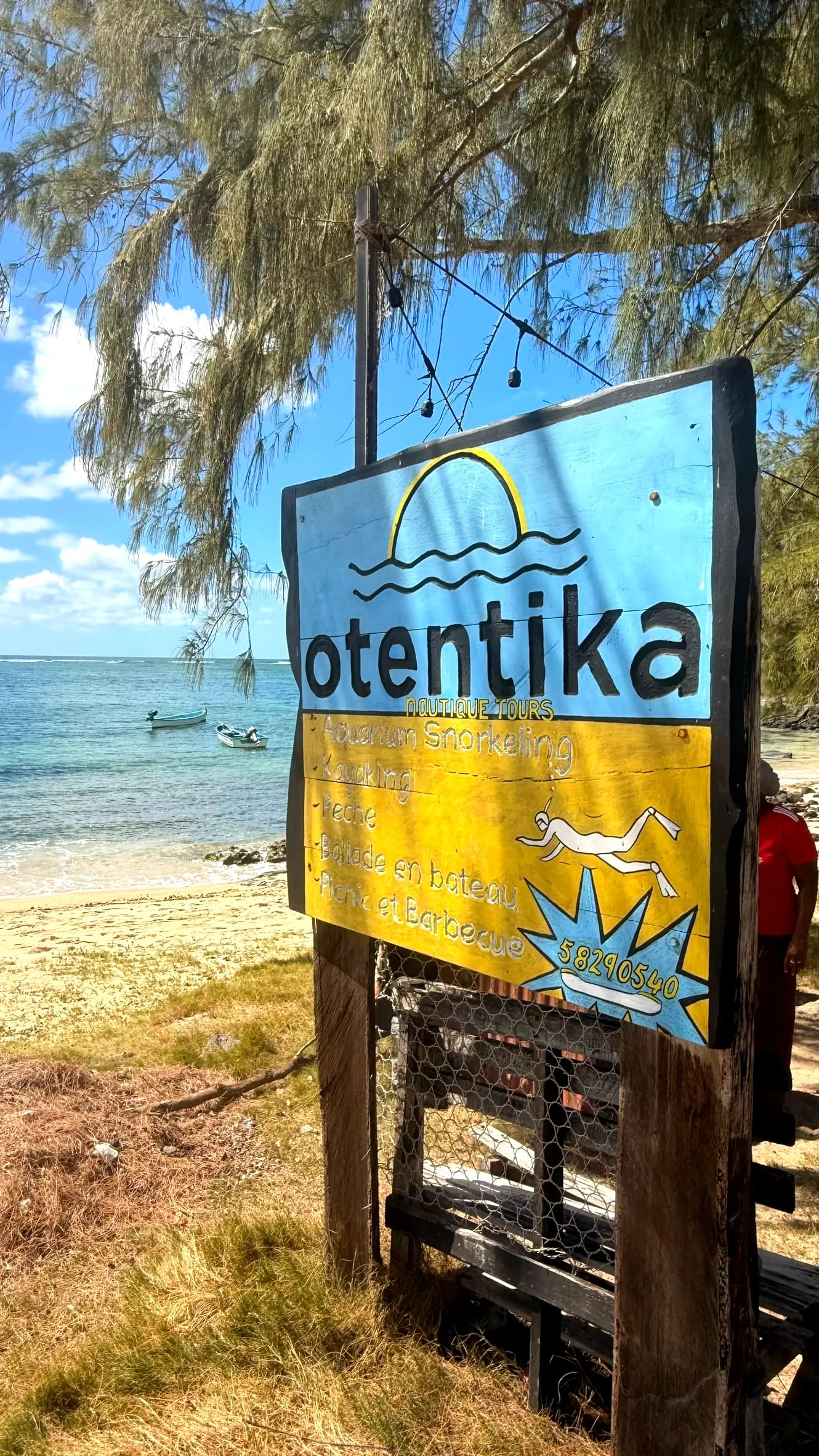 La pancarte peinte à la main d'Otentika, plantée face au lagon de Rivière Banane