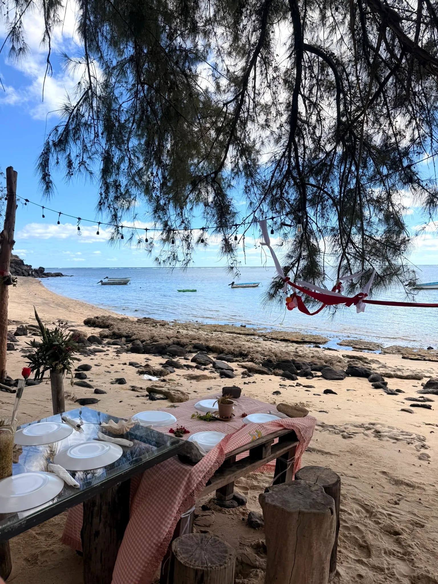 La Table d'Otentika dressée sous les filaos, nappe à carreaux face au lagon de Rivière Banane